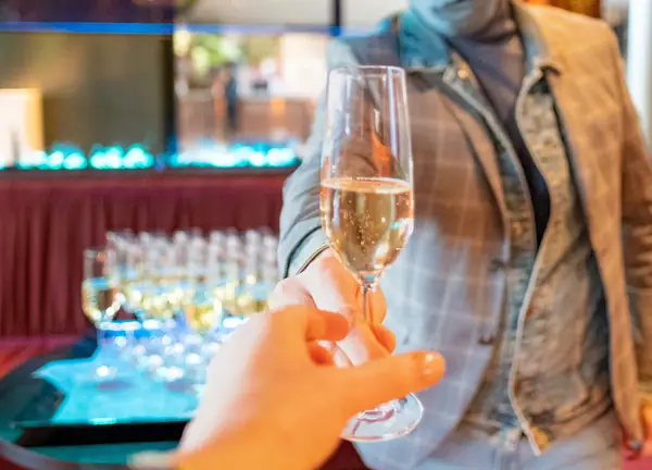 Glas bubbels wordt aangereikt, rij glazen op achtergrond