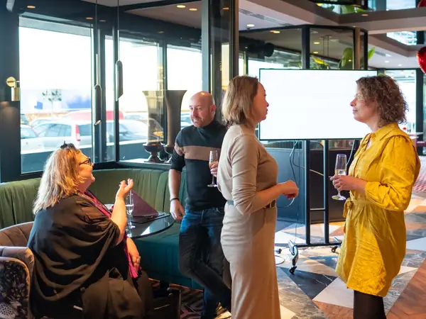 Vier deelnemers in gesprek met bubbels bij presentatiescherm