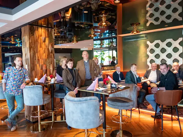 Deelnemers zittend en staand luisteren in lounge