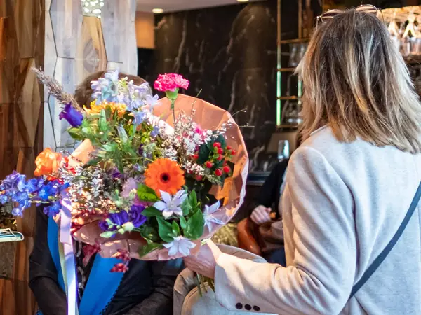 Kleurrijk boeket wordt overhandigd, vrouw van achteren