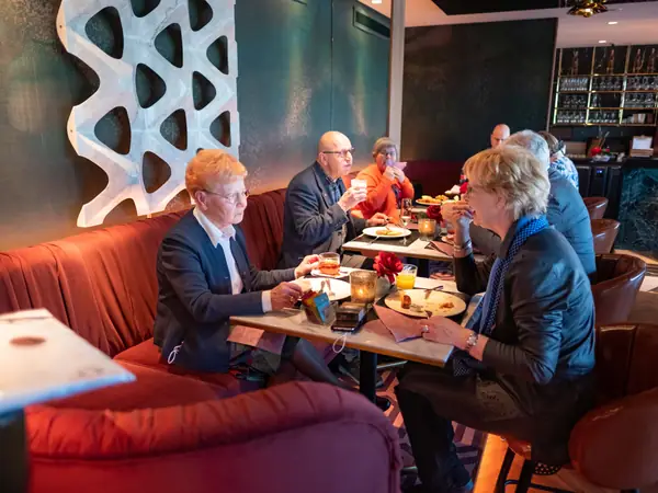 Groepje ontbijt op rode bank bij witte wanddecoratie