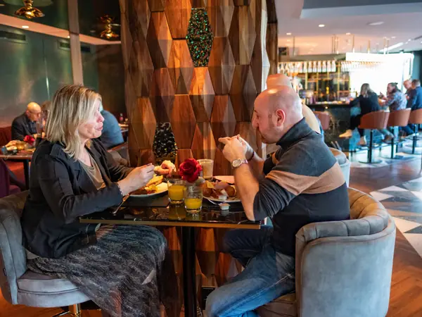 Duo in gesprek aan ontbijt bij houten zeshoekwand