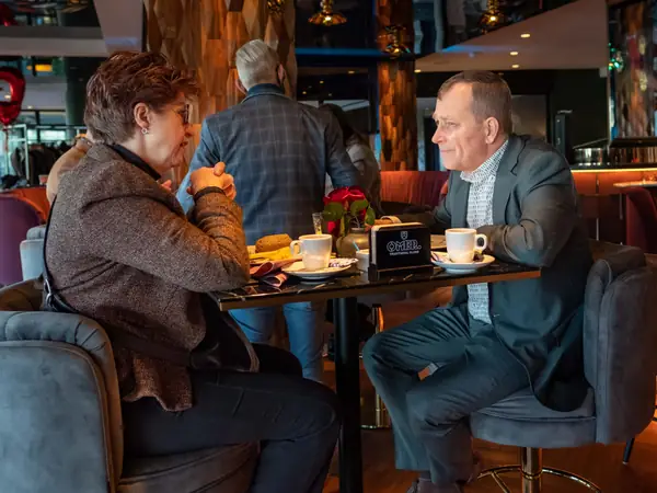 Man en vrouw in gesprek bij koffie en roos