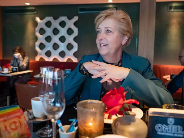 Lachende vrouw aan tafel met roos en kaars