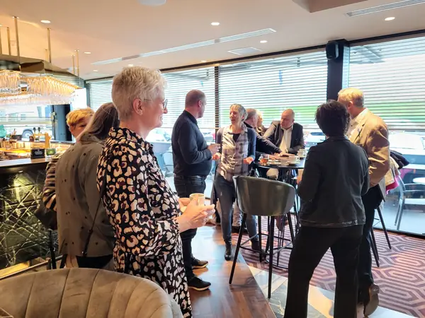 Lachende vrouw met koffie, groepjes in gesprek bij bar