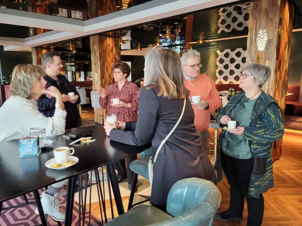 Kring deelnemers met koffie in gesprek rond statafel