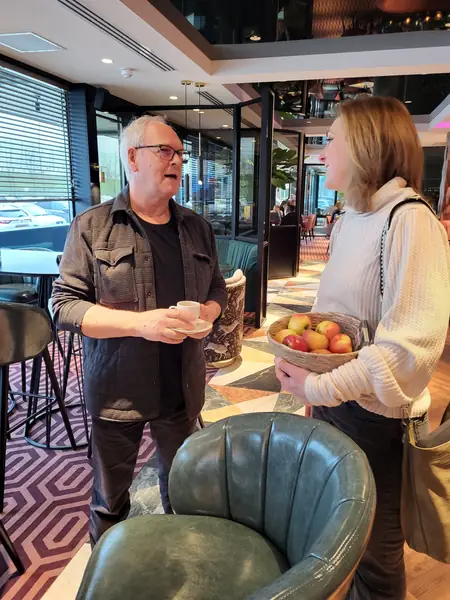 Man met koffie praat met vrouw met appelmand