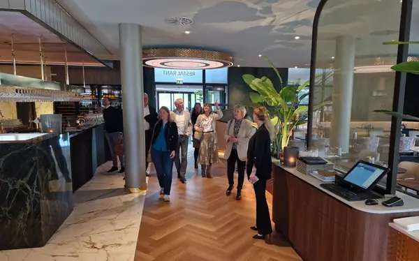 Groep loopt rondleiding door restaurant, vrouw wijst omhoog