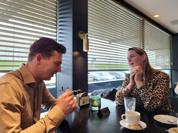 Man en vrouw in levendig gesprek aan tafel bij raam